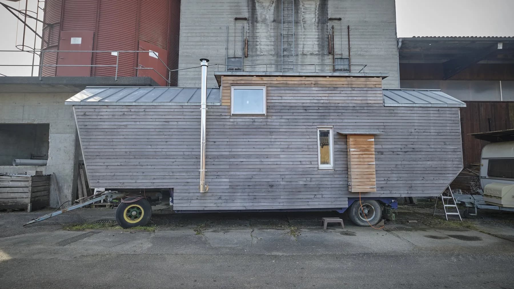 Aussenansicht des Tiny House auf dem Anhänger vor einem Hof