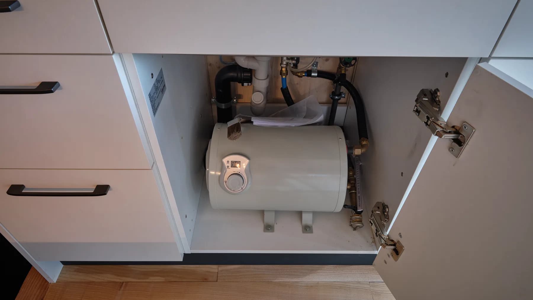 Boiler und Leitungen im Unterschrank unter der Spüle. Von aussen kann das Wasser mit einem gewöhnlichen Gartenschlauchanschluss angeschlossen werden.