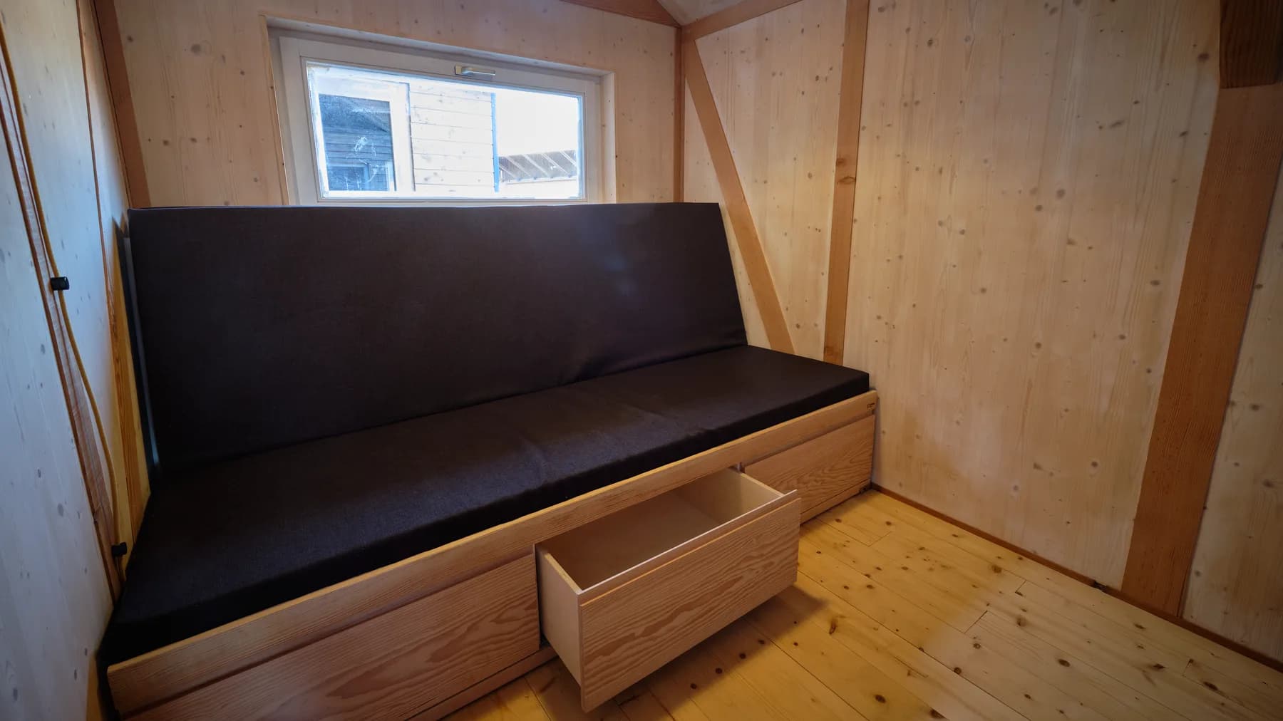 Das Sofa kann als Bett transformiert werden und bietet Platz für 2 Personen. Drei Schubladen unter dem Sofa bieten Stauraum. Die Bettwäsche kann hinter der Rückenlehne im Korpus verstaut werden.